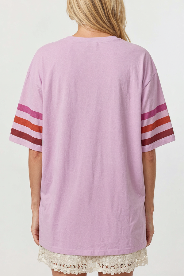Person wearing a light purple tunic with red and white stripes on sleeves against a white background
