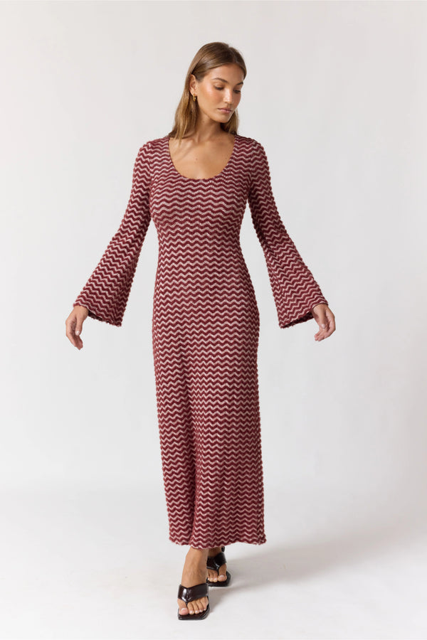 Woman wearing a long, patterned dress on a white background