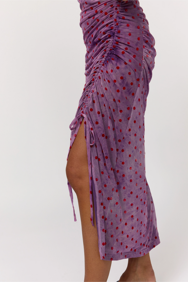 Purple dress with red polka dots and a high slit on a white background