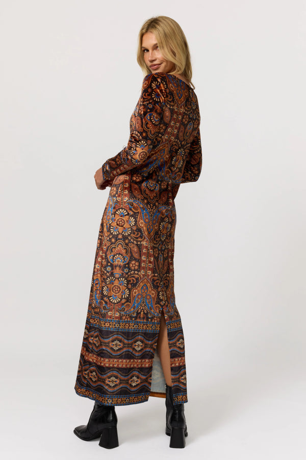 Woman wearing a long patterned dress on a white background