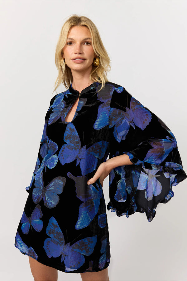 Woman wearing a black dress with blue butterfly patterns on a white background