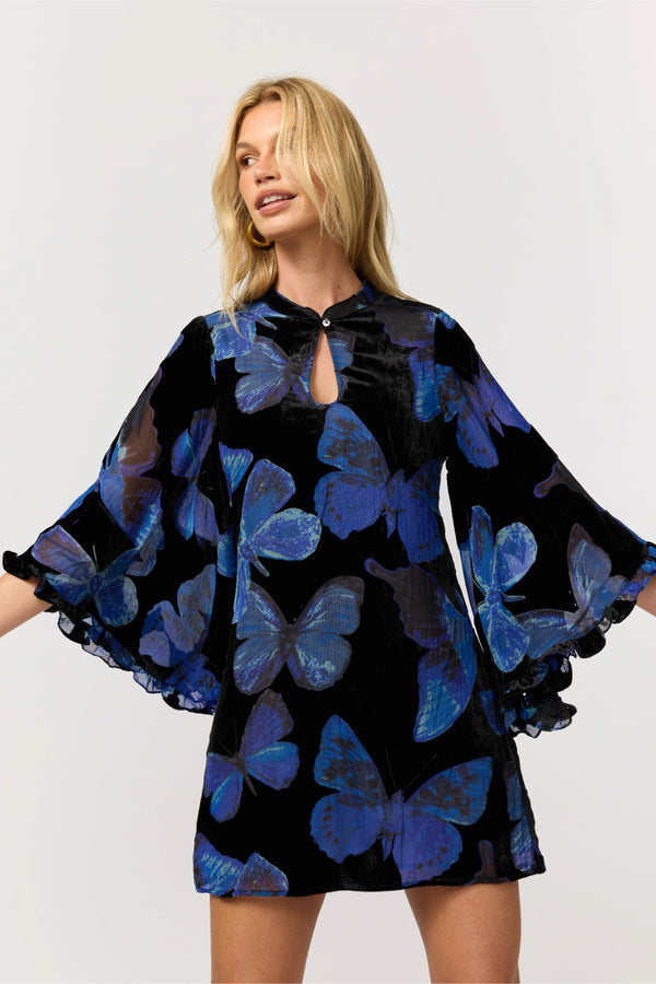 Woman wearing a black dress with blue butterfly patterns on a white background