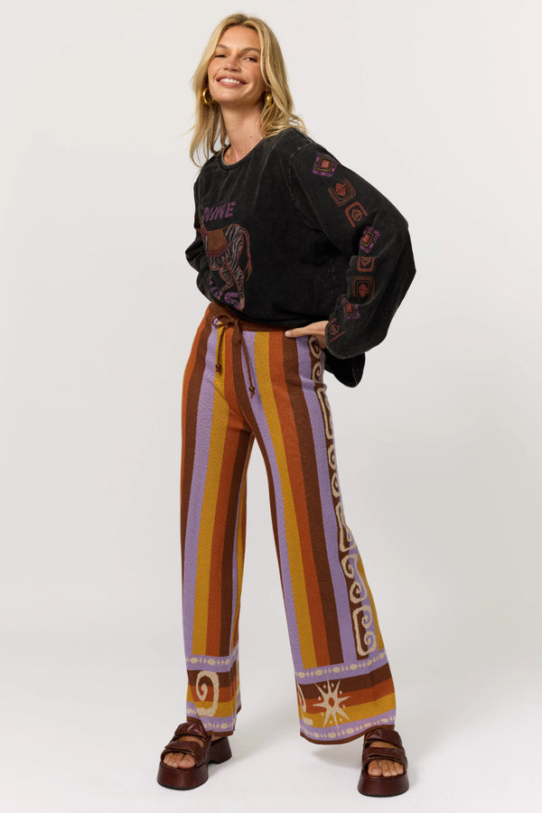 Woman wearing a black sweater and colorful striped pants on a white background