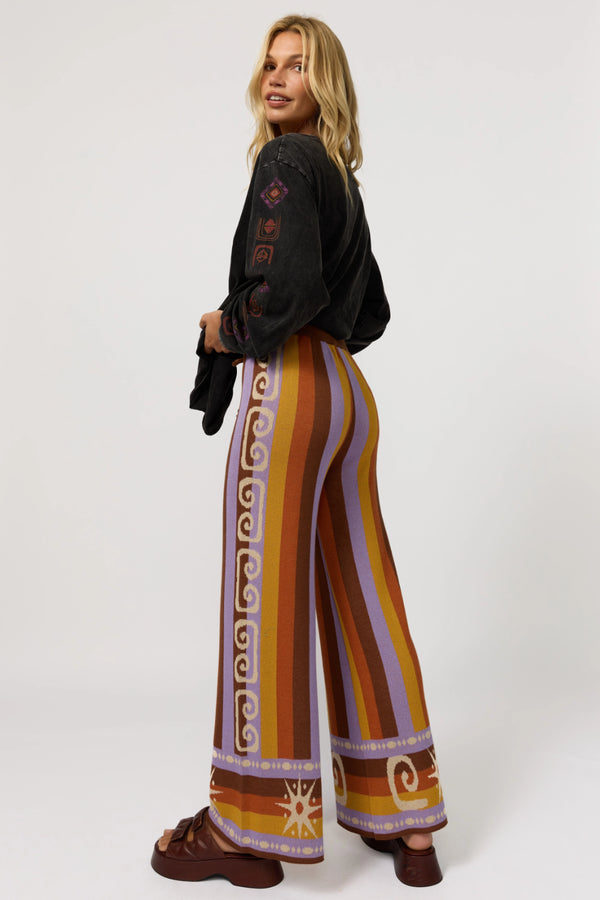 Woman wearing a black top and colorful patterned pants on a white background