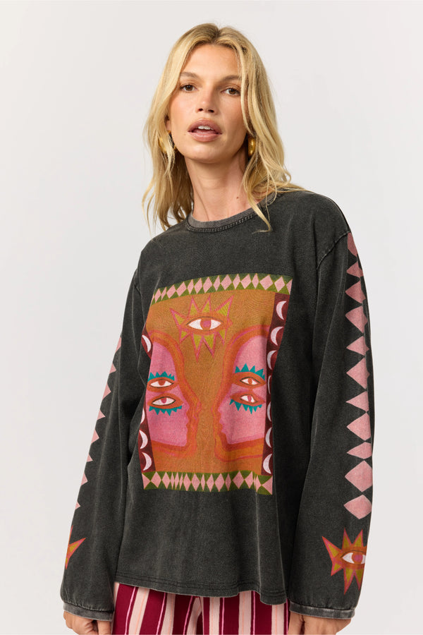 Woman wearing a black sweater with colorful abstract face design on a white background