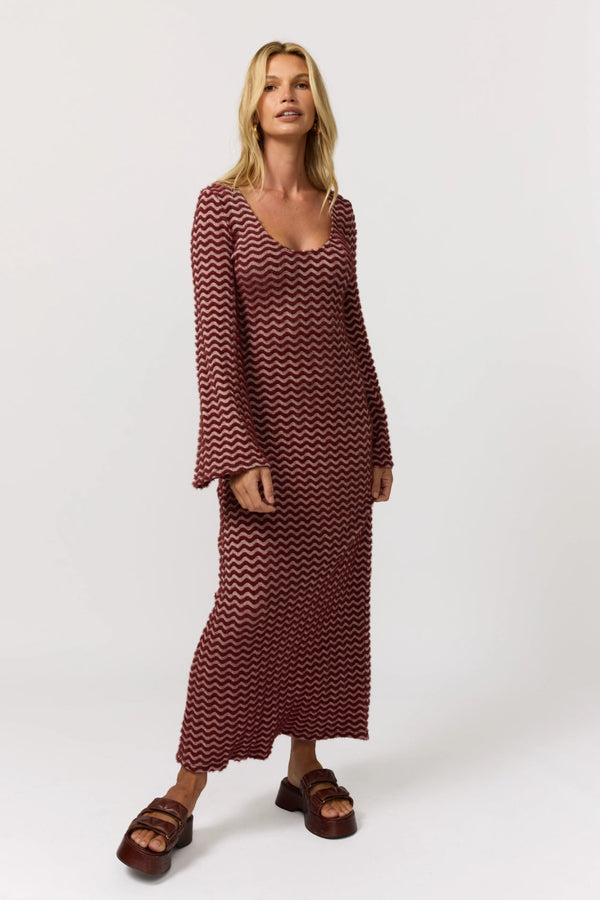 Woman wearing a burgundy chevron patterned dress on a white background