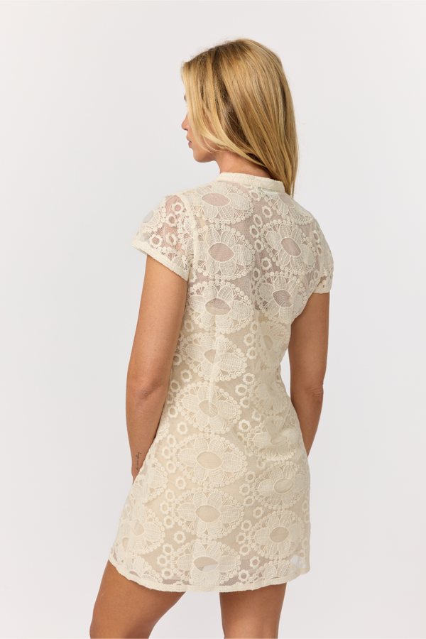 Woman wearing a beige lace dress on a white background