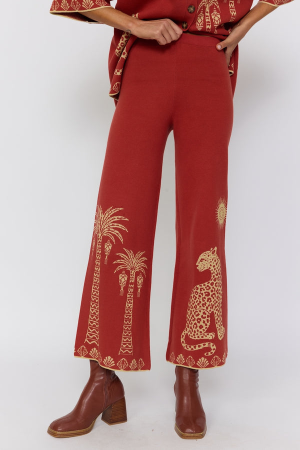 Red pants with gold embroidery worn by a person on a white background