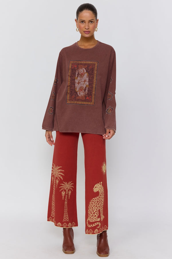 Woman wearing a brown top and red pants with patterns on a white background