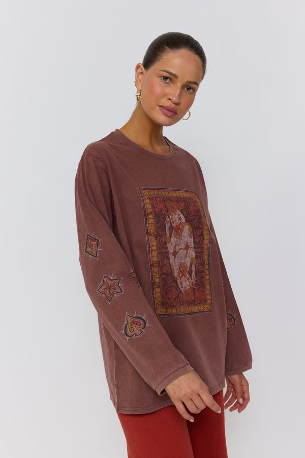 Woman wearing a brown long-sleeve top with embroidered designs on a white background