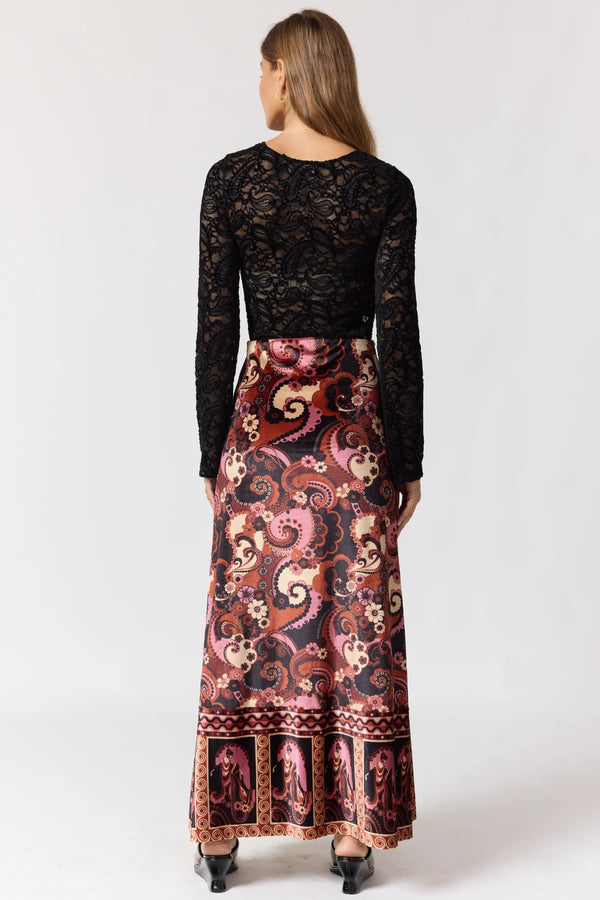 Woman wearing a black lace top and patterned skirt on a white background