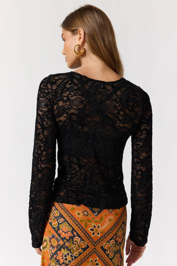 Woman wearing a black lace top with a patterned orange skirt on a white background