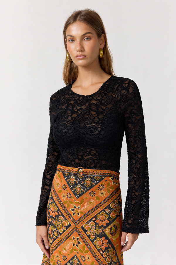 Woman wearing a black lace top and patterned orange skirt on a white background