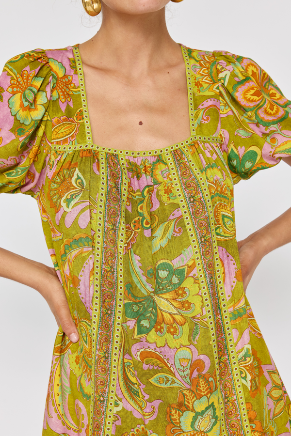 Woman wearing a colorful patterned dress with a plain background