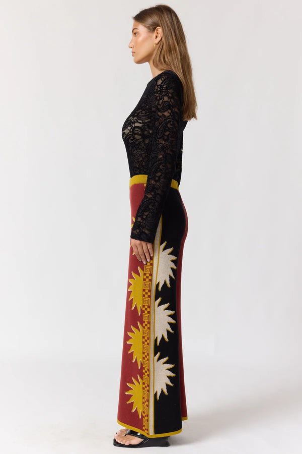 Woman wearing a black lace top and a long skirt with a sun pattern on a white background