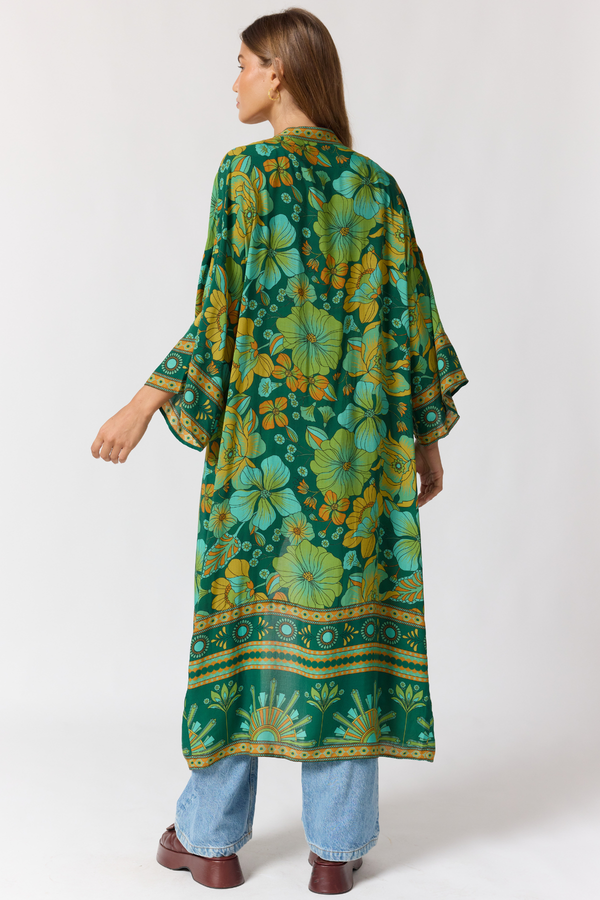 Woman wearing a green floral kimono-style garment on a white background