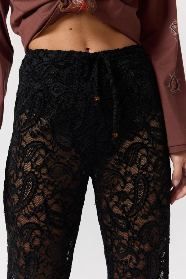 Black lace pants worn by a person with a brown jacket.
