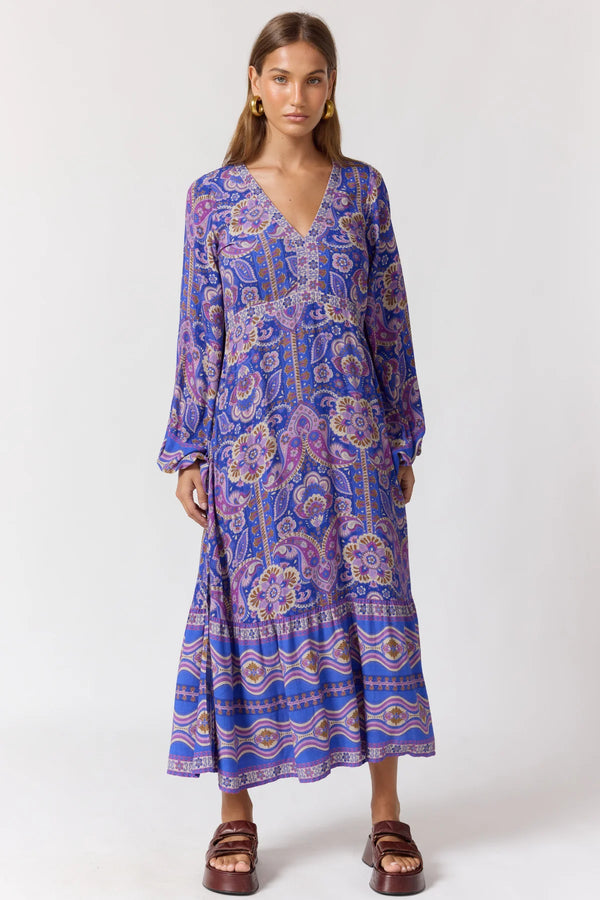Woman wearing a long-sleeve, patterned dress against a white background
