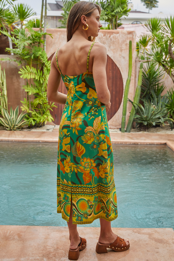 Woman in a colorful dress standing by a pool with plants in the background