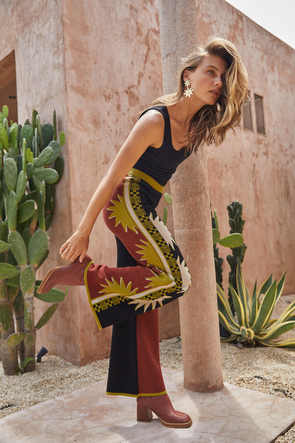 Woman in a colorful pants standing in front of a cactus plant.