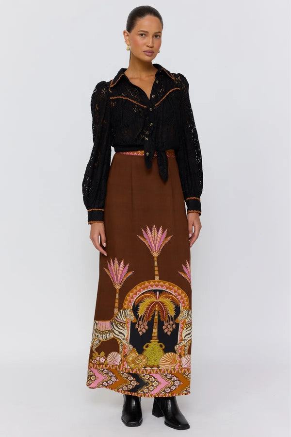 Woman wearing a black top and brown patterned skirt on a white background