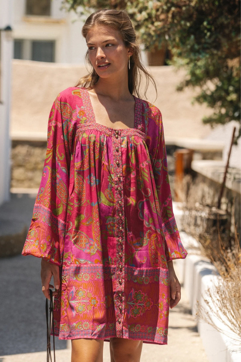 Woman wearing a pink patterned dress standing outdoors.