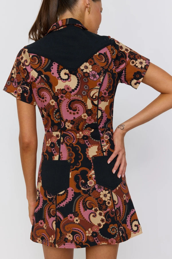 Woman wearing a patterned dress with black accents on a white background