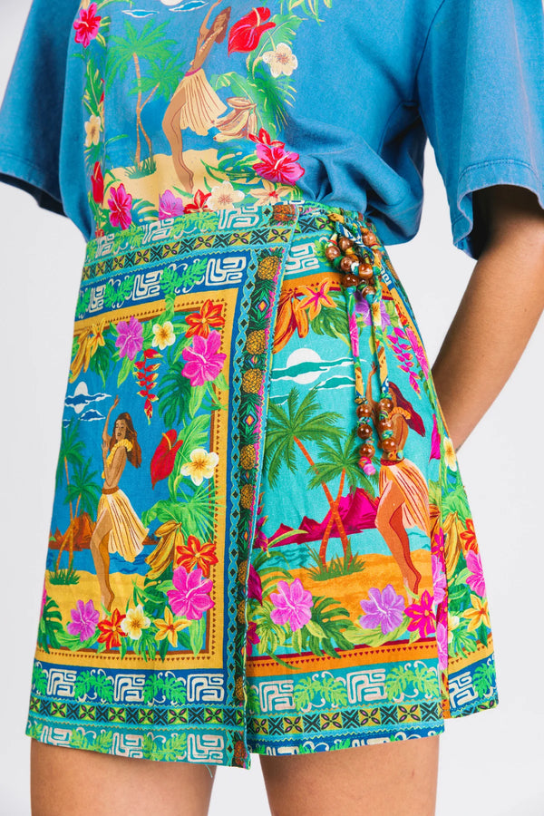 Person wearing a colorful tropical-themed apron over a blue shirt.