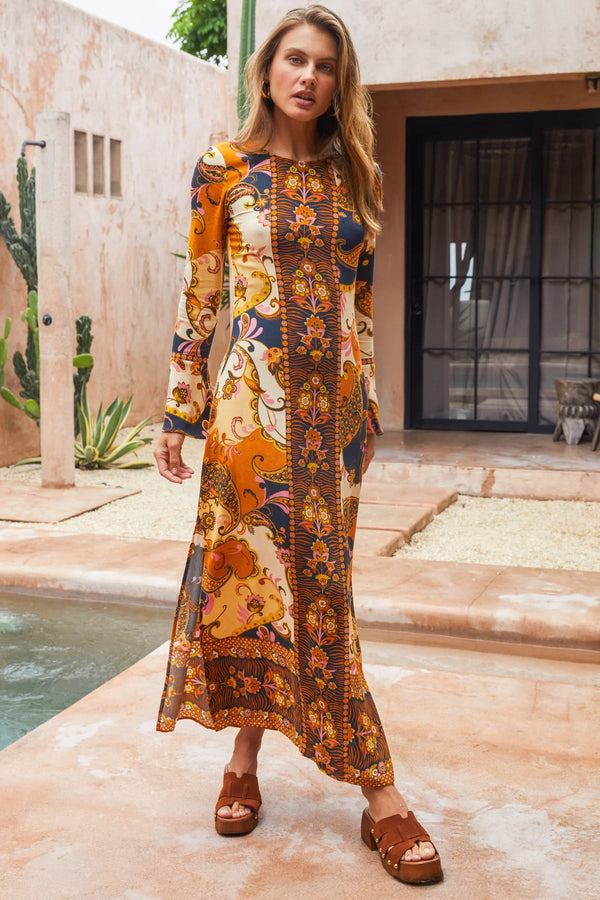 Woman wearing a patterned dress standing by a poolside.