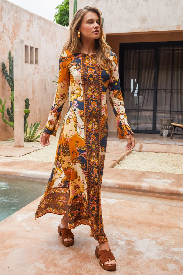 Woman wearing a patterned dress standing by a poolside.