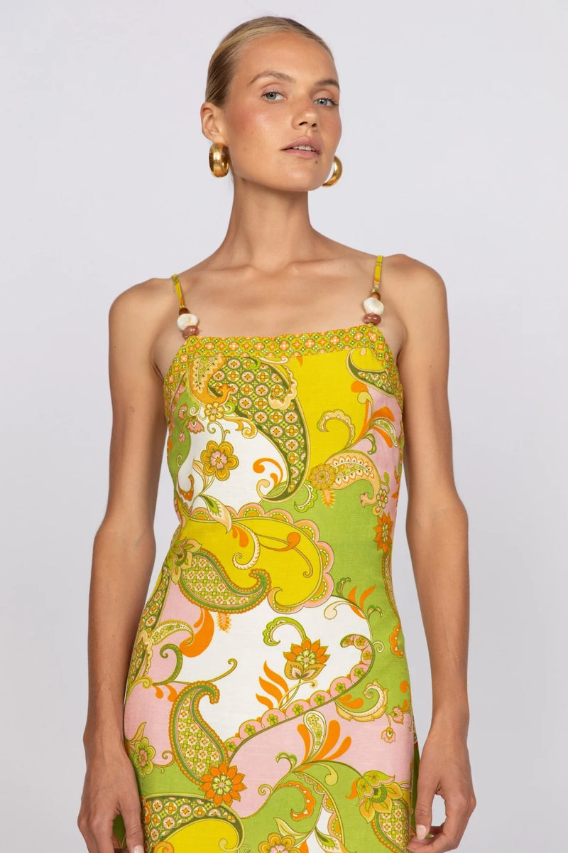 Woman wearing a colorful patterned dress on a plain background