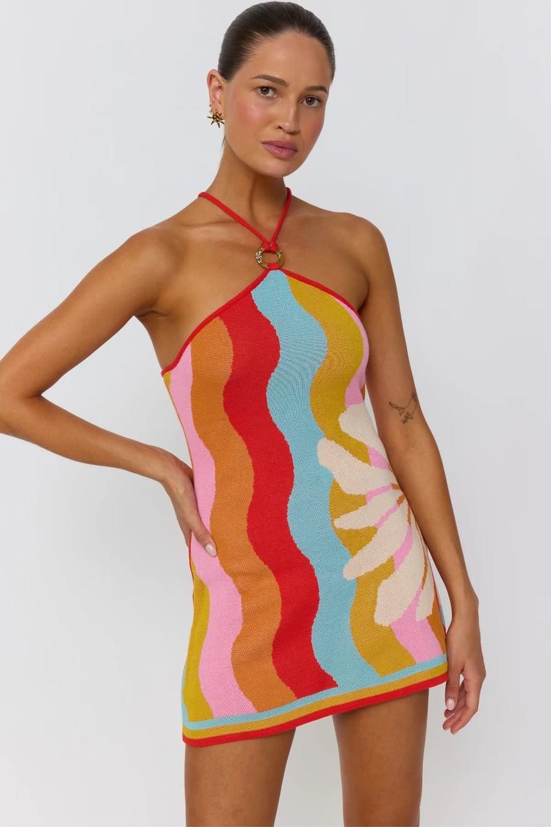 Woman wearing a colorful patterned dress on a plain background