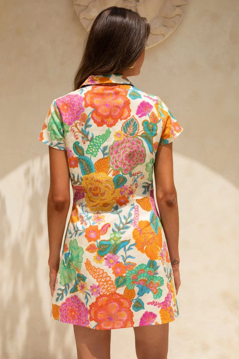 Woman wearing a colorful floral dress against a neutral background