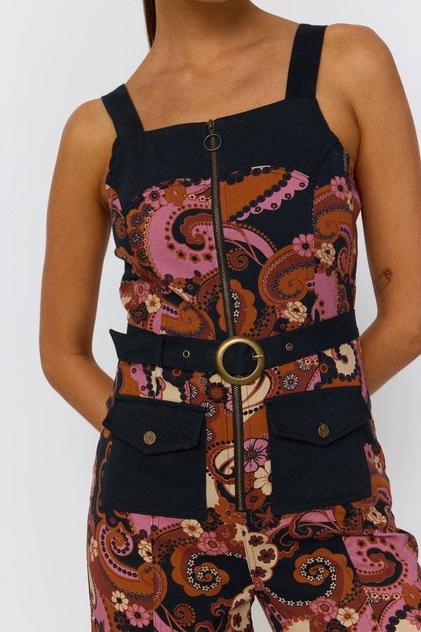 Person wearing a patterned dress with a belt and large buckle on a white background