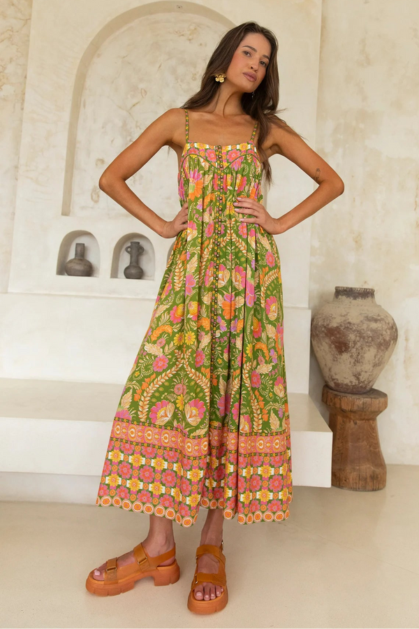 Woman wearing a colorful floral dress standing in a room with decorative elements.