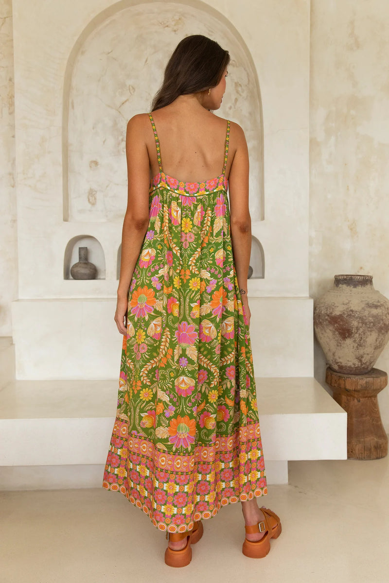 Woman wearing a colorful floral dress in an arched stone room.
