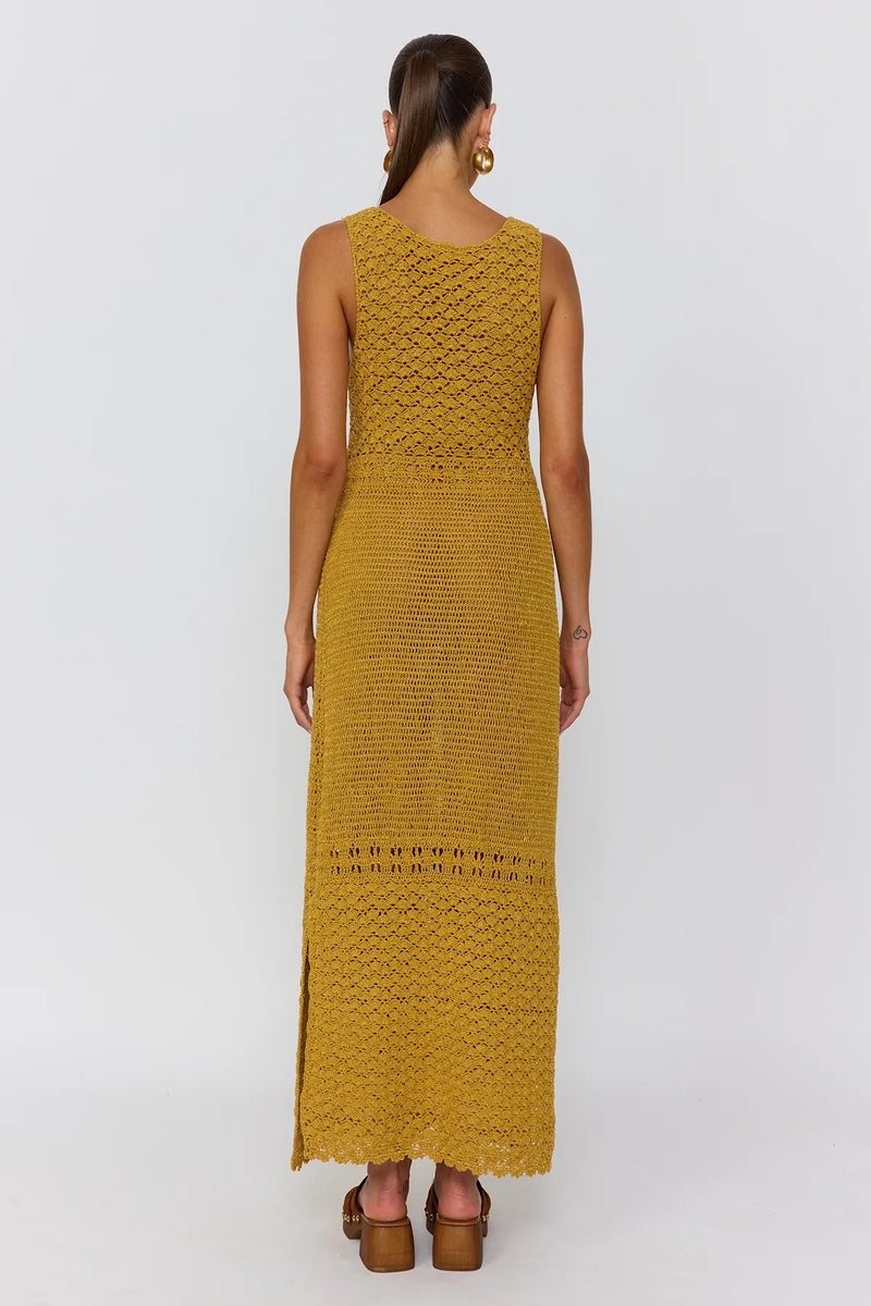 Woman wearing a mustard yellow dress with a textured pattern on a white background