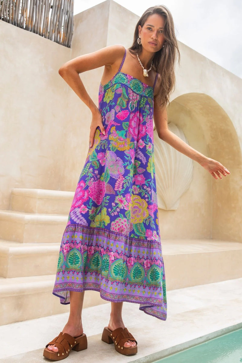 Woman wearing a colorful floral dress standing outdoors near steps.