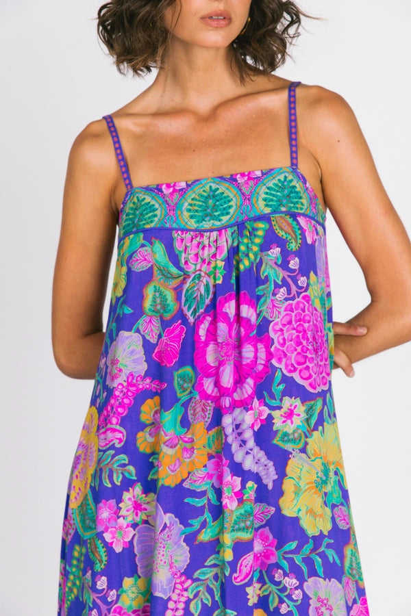 Woman wearing a colorful floral dress with a purple background