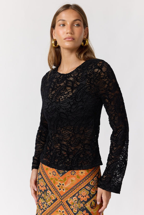 Woman wearing a black lace top with an orange patterned skirt on a white background