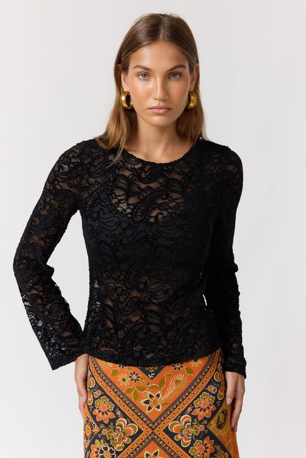 Woman wearing a black lace top and patterned skirt on a white background