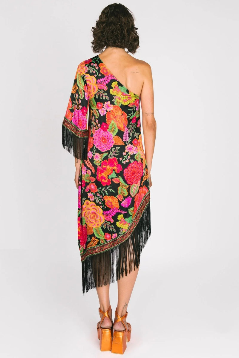 Woman wearing a colorful floral one-shoulder dress with fringes on a white background