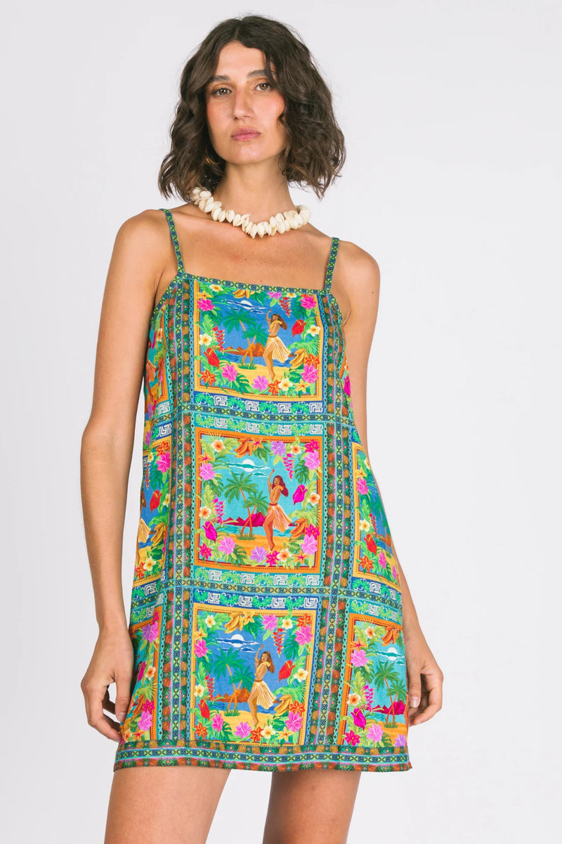 Woman wearing a colorful dress with a pattern of women in various poses against a white background