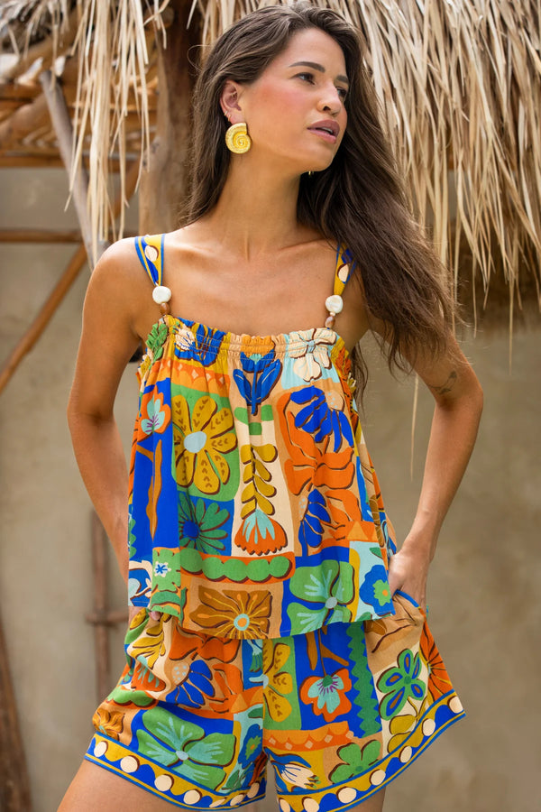 Woman wearing a colorful floral dress with a thatched roof background