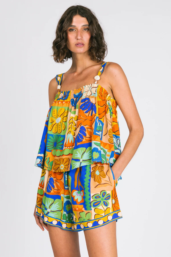 Woman wearing a colorful floral top and shorts on a white background