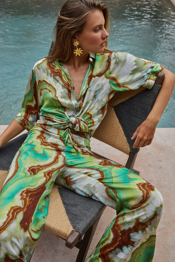 Woman in a tie-dye outfit sitting by a pool