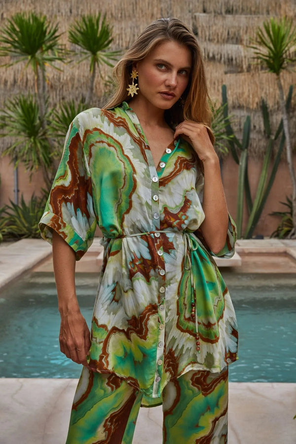 Woman wearing a patterned outfit by a pool with plants in the background