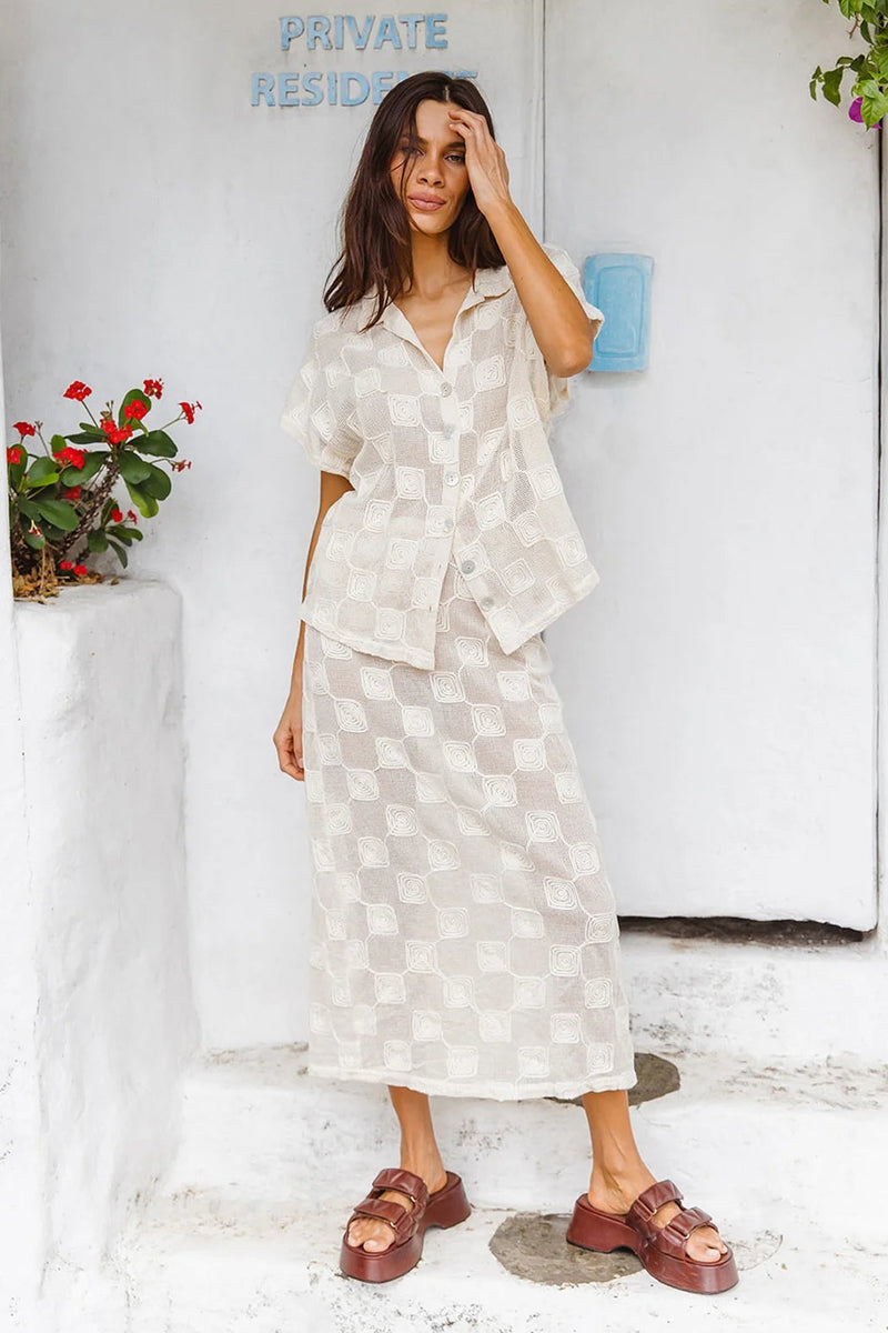 Woman in a white checkered dress standing in front of a white door with 'Private Residence' sign.