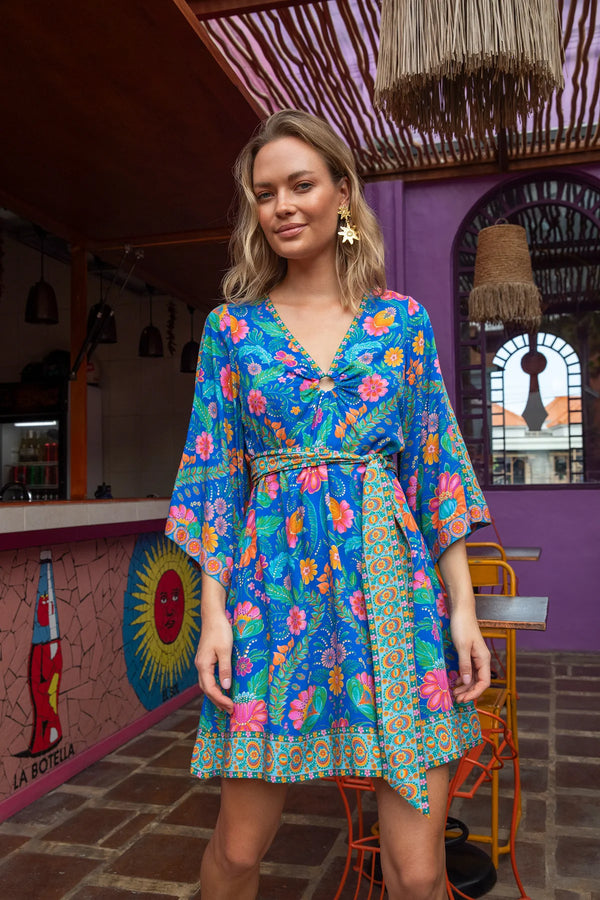 Woman wearing a colorful floral dress in a vibrant indoor setting.