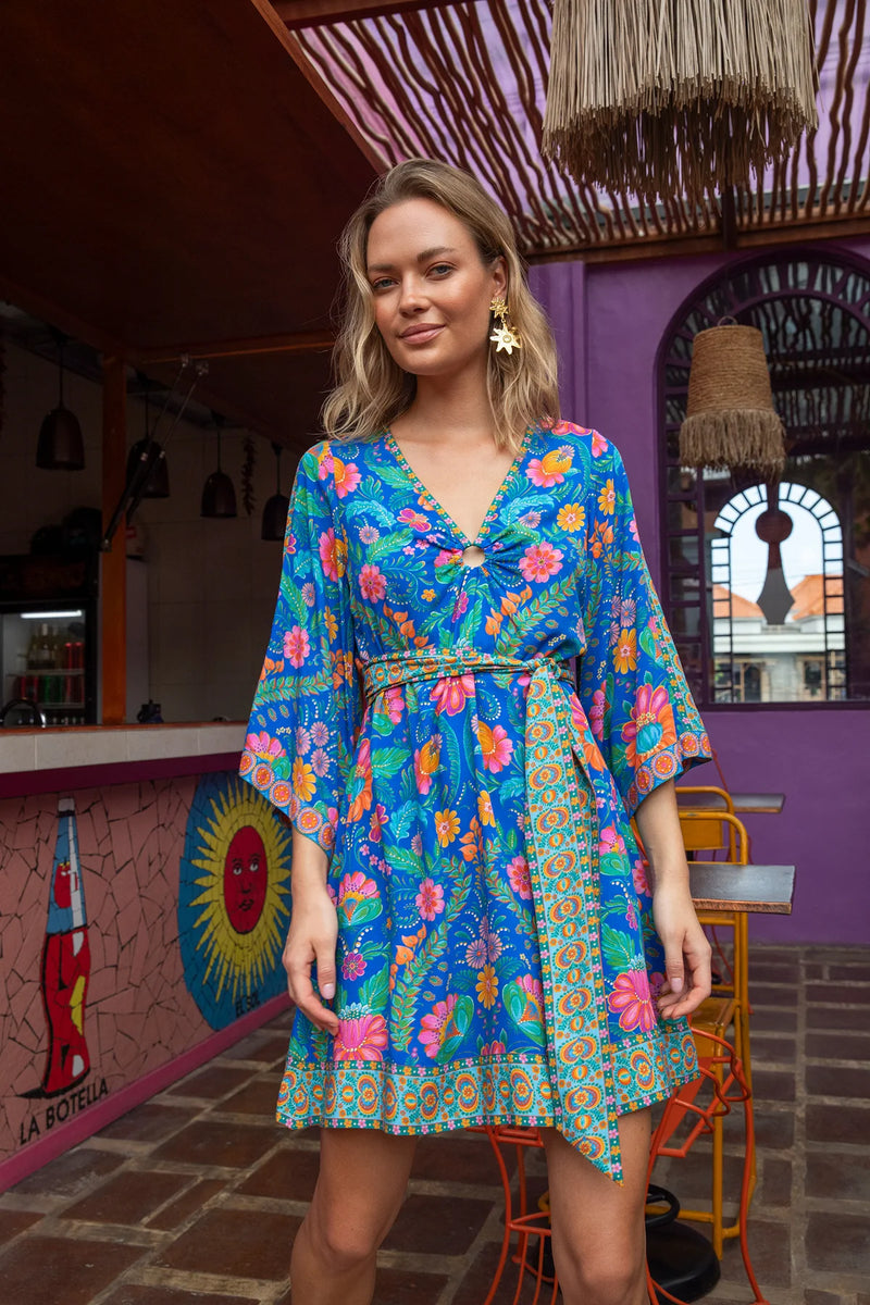 Woman wearing a colorful floral dress in a vibrant indoor setting.
